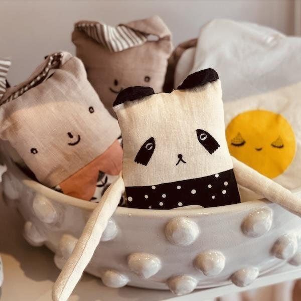 Plush animal toys in a white polka-dot bowl, including a panda and yellow chick.
