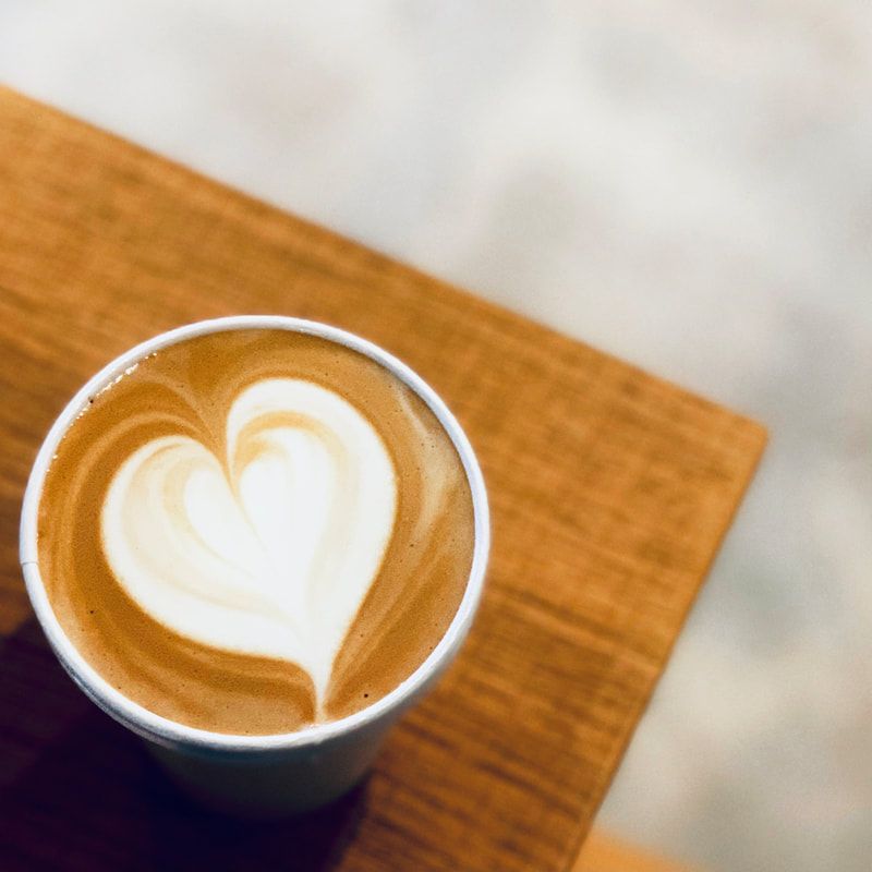 Cup of latte with heart-shaped foam on a wooden table.