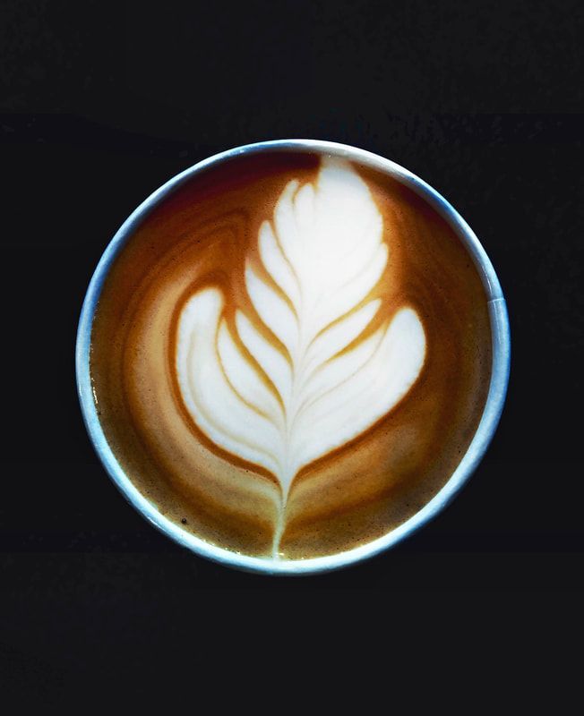 Latte with white leaf latte art in a dark cup on a black background