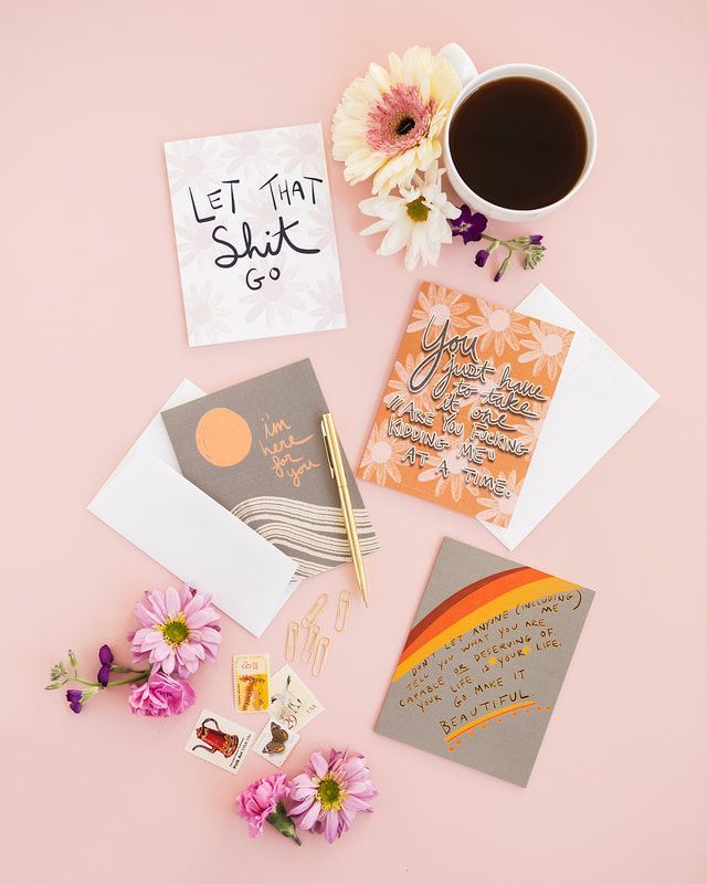 Flat lay of handmade greeting cards, flowers, and a cup of coffee on a pink background