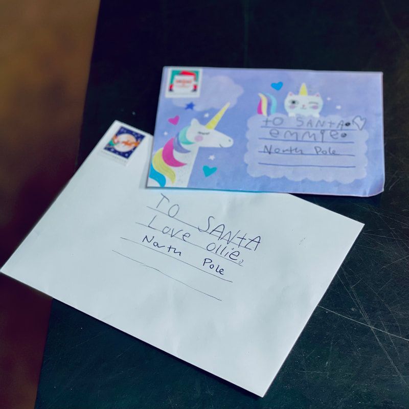 Two handwritten envelopes with colorful decorations on a dark table.