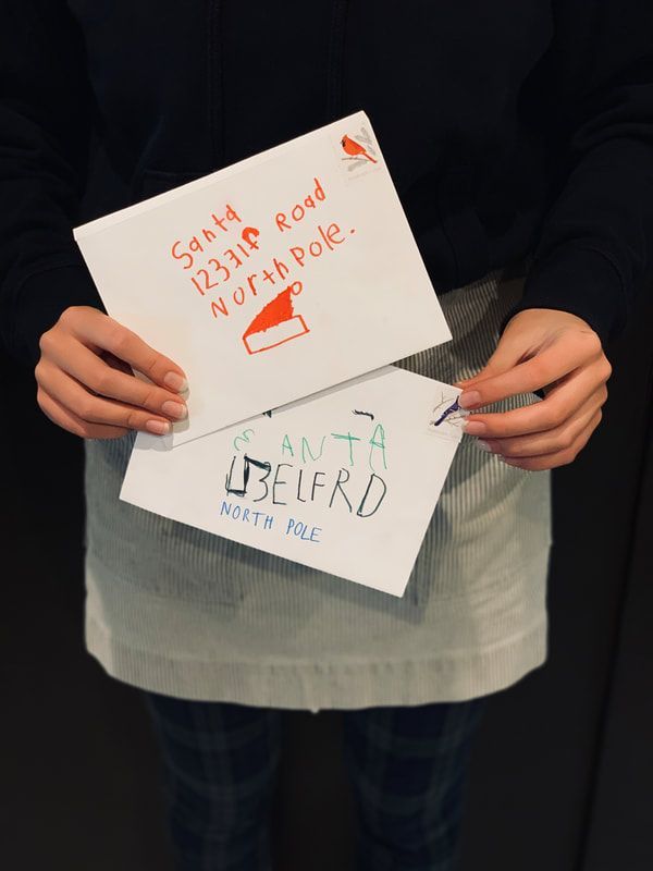 Person holding two handmade paper signs, one white with red writing and one gray with green writing.