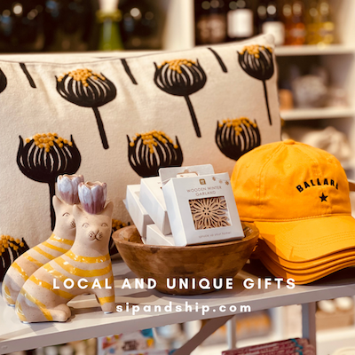 Gift display with yellow cap, patterned socks, cards, and sign reading “Local and Unique Gifts”