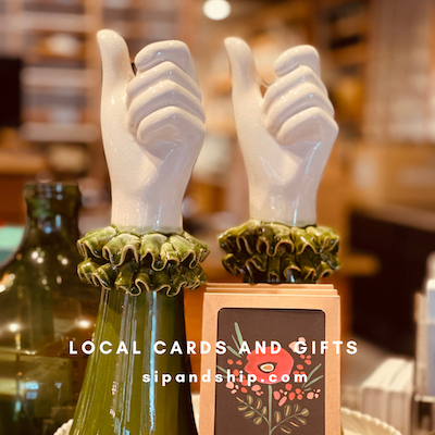 Two white thumbs-up hand sculptures on wooden stands in a shop display