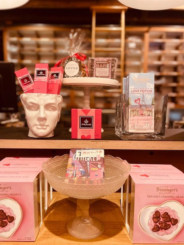 Luxury perfume display on shelves, featuring red and pink packaging with a white sculpted face decor piece.