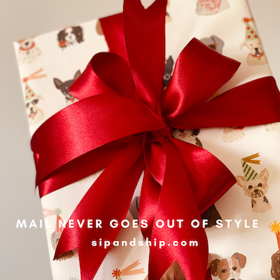 Gift wrapped in cream paper with a large red ribbon bow and the text “MAI NEVER GOES OUT OF STYLE.”