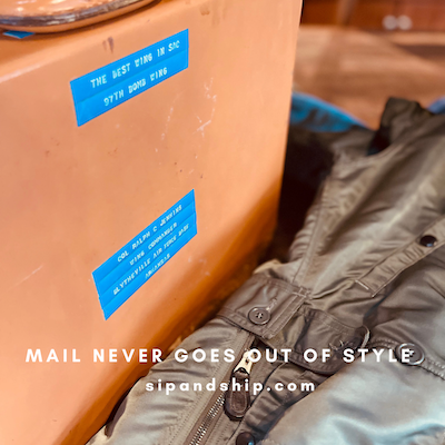 Blue labels on an orange suitcase beside a gray jacket, with 