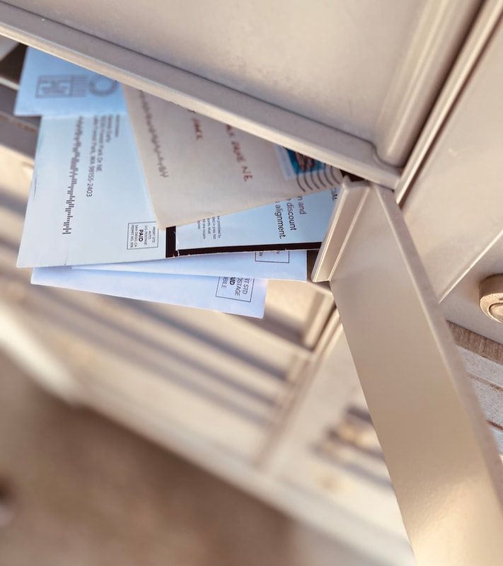 Close-up of blue envelopes and a mail slot on a beige metal surface.