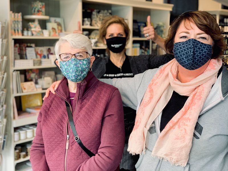 Three masked people standing in a store aisle, with shelves of products behind them.