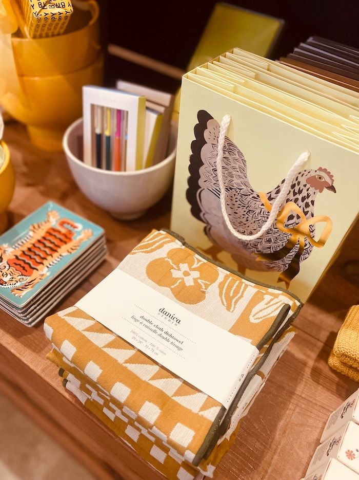 Desktop with patterned stationery, greeting cards, and a white bowl holding colorful cards in warm sunlight