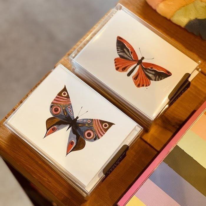 Two butterfly illustrations on open cards in a wooden display box