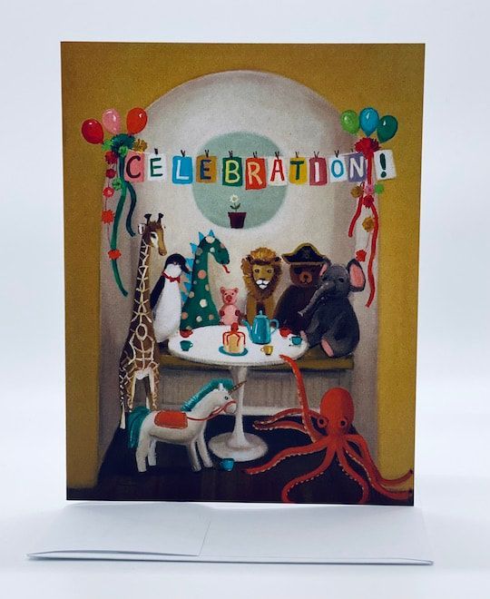 Festive tabletop scene with “CELEBRATION!” banner, balloons, cakes, and animal figurines in a display box