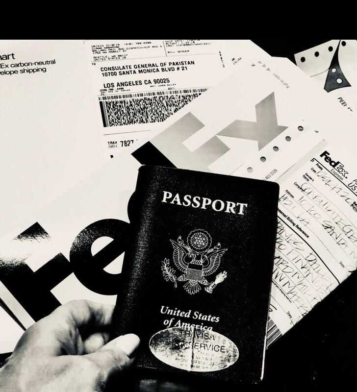 Hand holding a U.S. passport over travel documents and airplane tickets