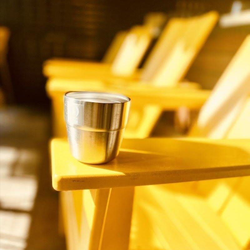 Metal cup on a yellow chair in a sunlit seating area