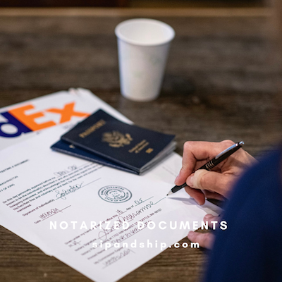 Hand signing a notarized document beside a passport and coffee cup on a wooden table.