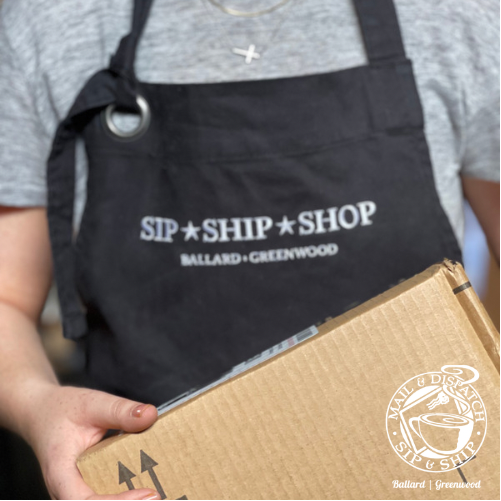 Person in a black apron holding a cardboard package, with “SIP SHIP SHOP” text visible.