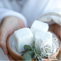 White sugar cubes in a small bowl, held in hands with a white background