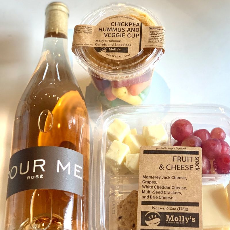 Wine and three food containers: veggie sticks, cheese, and fruit on a light background