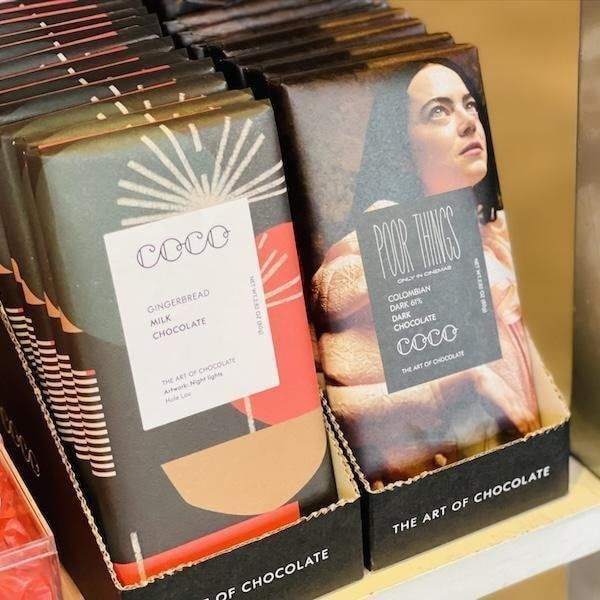Stacked COCO chocolate bars in colorful wrappers on a store display shelf.