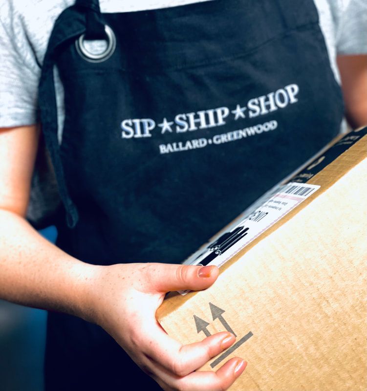 Person holding a cardboard package with a Sip + Ship + Shop apron visible