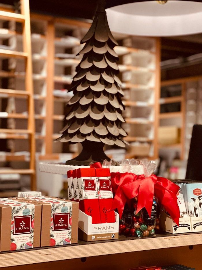 Holiday gift display with stacked red and white packages and a decorative paper tree in a store