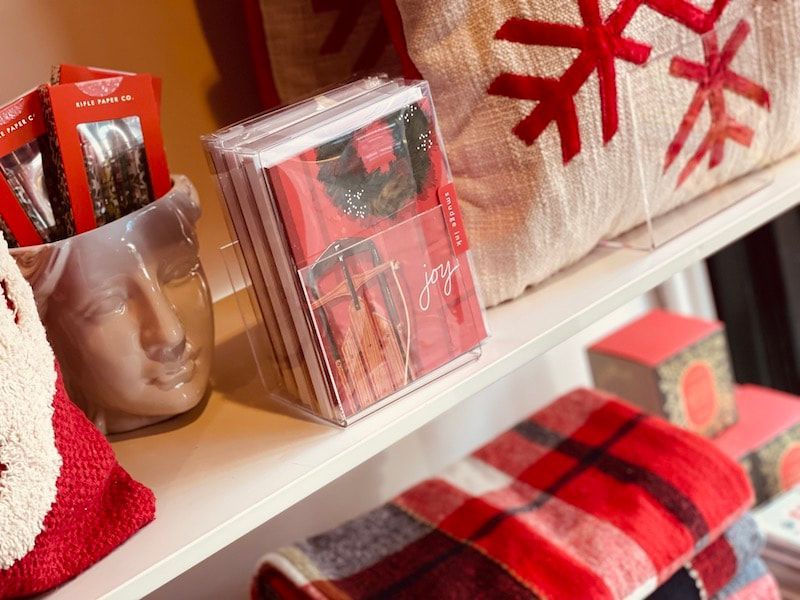 Holiday gifts and red plaid decor on a shelf, with wrapped boxes and festive red accents