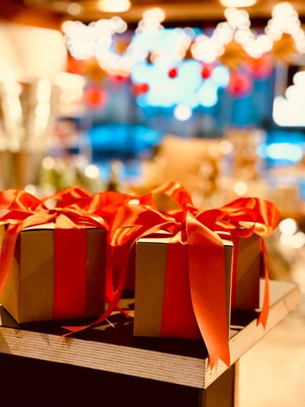 Red gift boxes with gold ribbons on a table at a festive, blurred holiday market