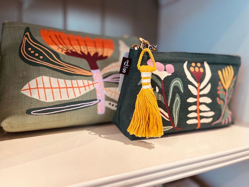 Embroidered fabric boxes with floral patterns and a yellow tassel on a shelf