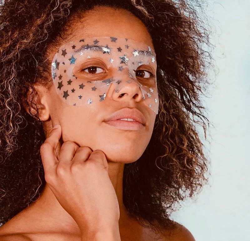 Woman with star stickers on her face, posing against a light background