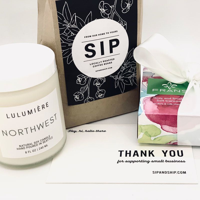 Gift boxes and candles with a thank-you card on a table, including a SIP package and Lulumière Northwest candle
