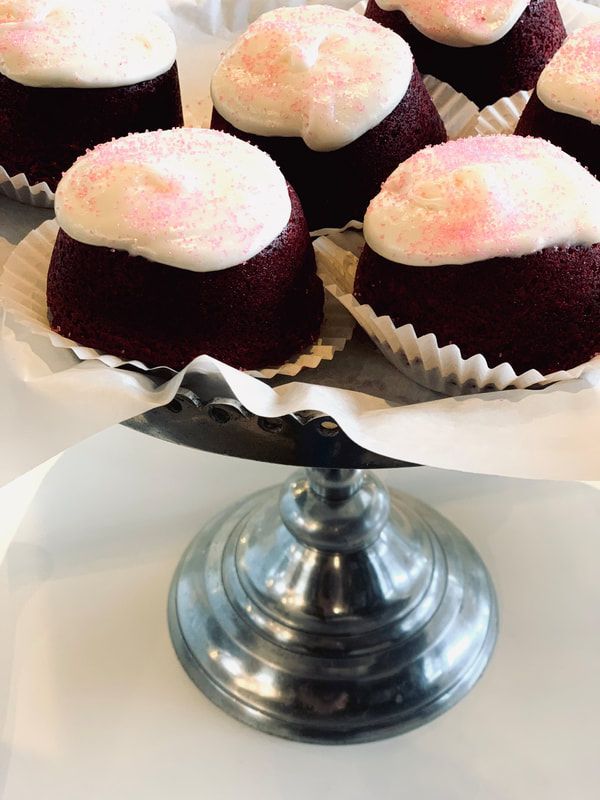 Tray of chocolate cupcakes topped with pink and white frosting on a silver stand