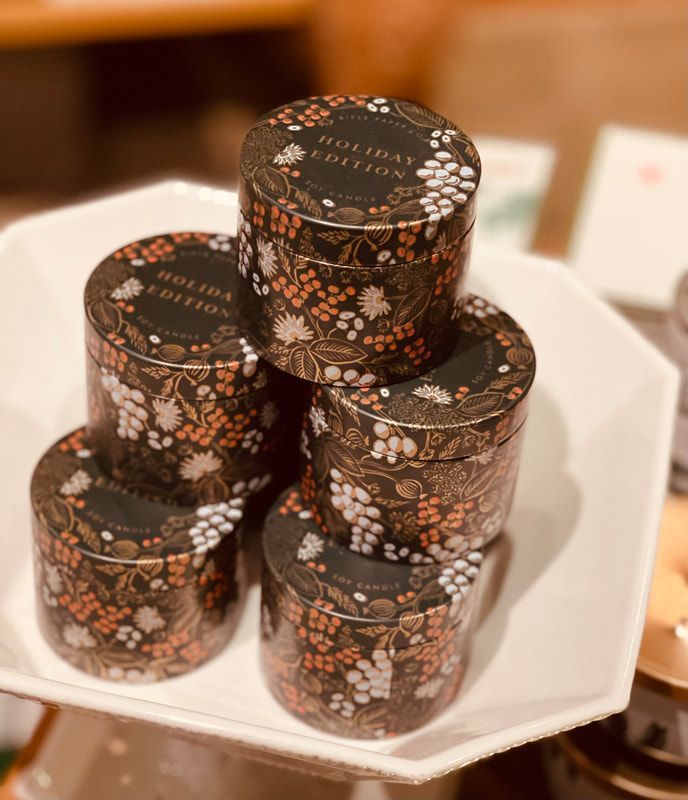 Stacked black floral tins on a white tray, with one small tin in front.