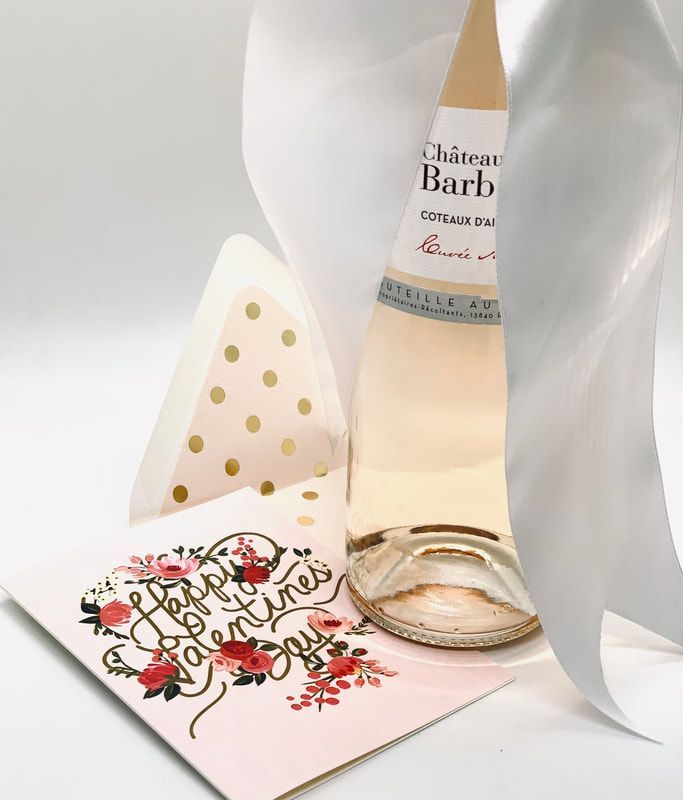 Bottle of Château Barb with a gold-dotted card and floral note card on a white surface