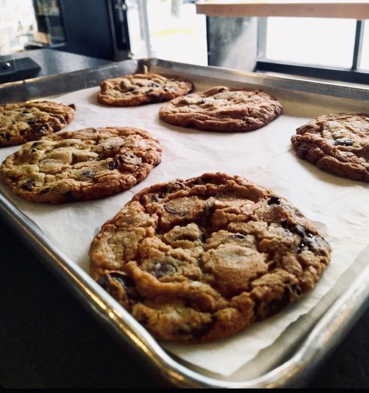 Fresh chocolate chip cookies cooling on a baking sheet by a window