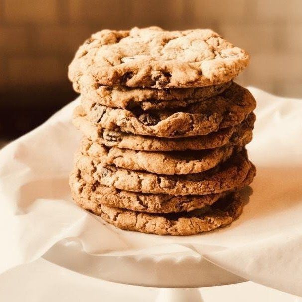 Stack of chocolate chip cookies on white parchment paper, with a warm brown background.