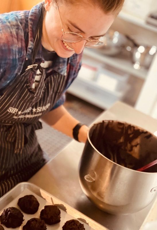 Chef in striped apron piping chocolate onto cookies in a kitchen