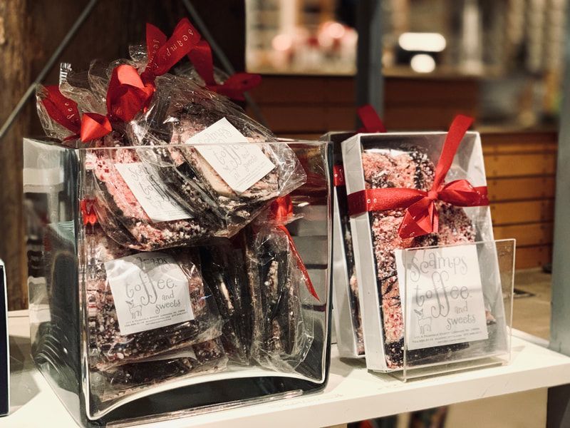 Gift baskets wrapped in clear plastic with red bows on a display shelf