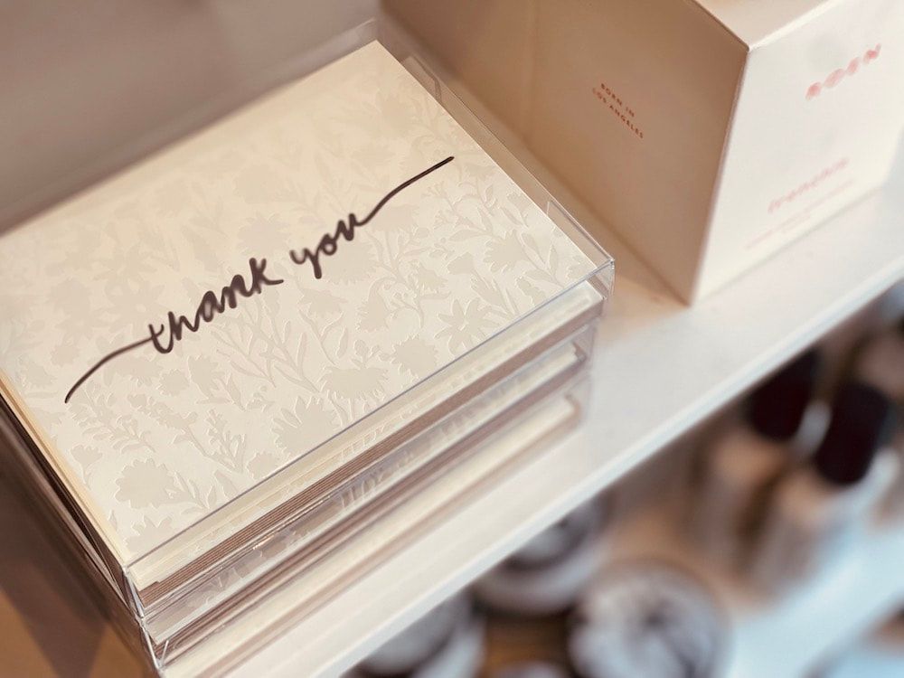 Stack of clear boxes with a white card that says “thank you” in cursive handwriting