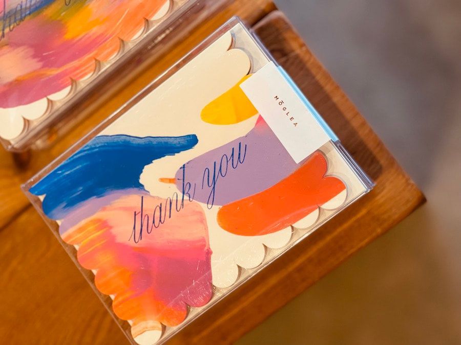 Colorful abstract art card in a clear box on a wooden table.
