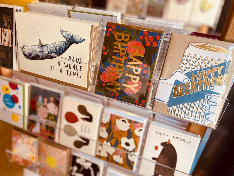 Greeting cards in a display rack, with colorful birthday and whale designs