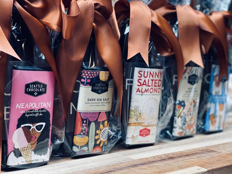 Assorted snack bags with brown ribbon bows on a shelf, including Neapolitan and salted almond flavors
