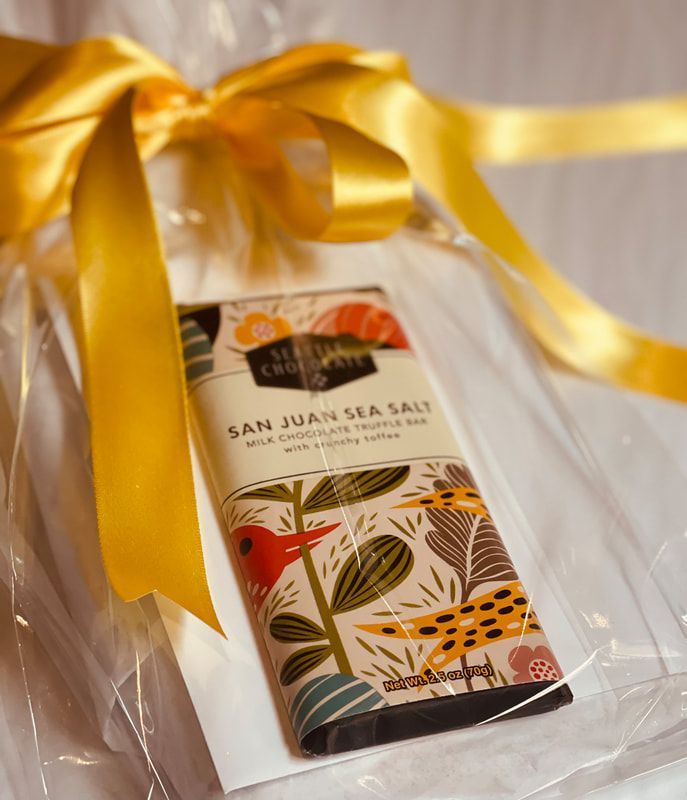 Gift-wrapped box with a yellow ribbon and a San Juan Sea Salt package on a white surface