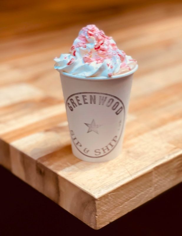 Cup of whipped dessert topped with pink drizzle on a wooden counter