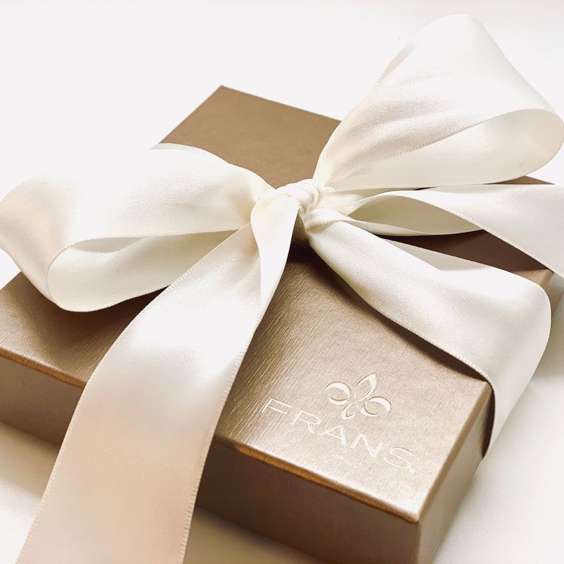Gold gift box with a large cream ribbon bow on top
