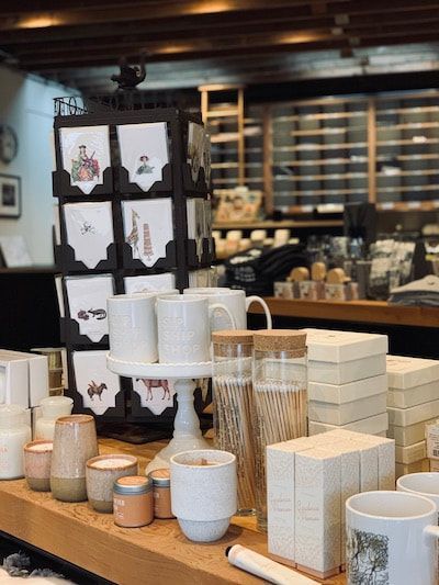 Ceramic mugs, cups, and vases displayed on wooden shelves in a pottery shop