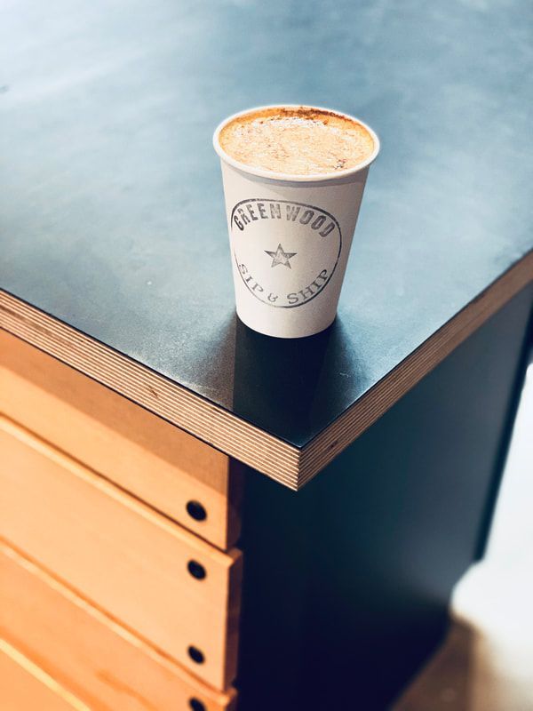 Paper coffee cup on a dark tabletop beside a wooden drawer unit