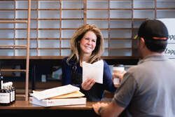 Two people talking at a desk in an office, with a smiling woman holding a document.