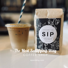 Iced coffee beside a bag labeled “SIP” in a coffee shop setting