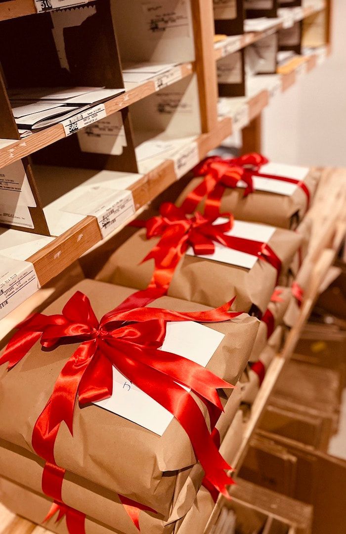Gift-wrapped packages with red ribbons lined up on shelves in a stockroom