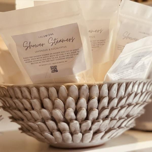 Decorative bowl holding cream-colored pouches of strawberry-scented bath tea or soap packages